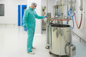 pharmaceutical factory man worker in protective clothing working with control panel in sterile working conditions
