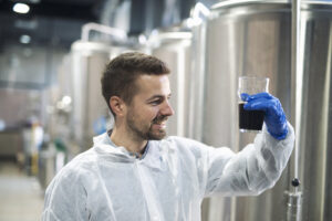 technologist checking product quality in beverage alcohol production plant.